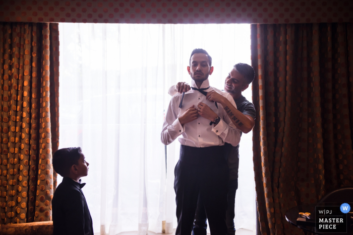 England wedding reportage photography at the Radisson Hotel, Heathrow	| The groom putting his tie on while Getting ready