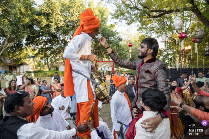 Hochzeitsfoto des Bräutigams in Ahmedabad, Indien, das dem Musiker sein Trinkgeld übergibt