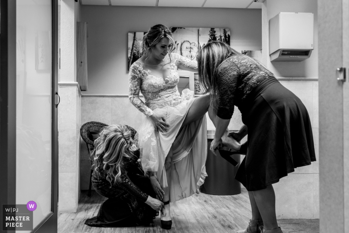 Imagem do casamento de South Lake Tahoe, Califórnia, de uma noiva recebendo ajuda com os sapatos antes do casamento