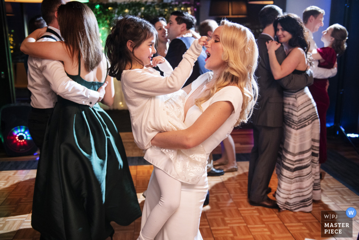 Legal Harborside, Boston, Massachusetts wedding image of flower girl pinching bride's nose while dancing 