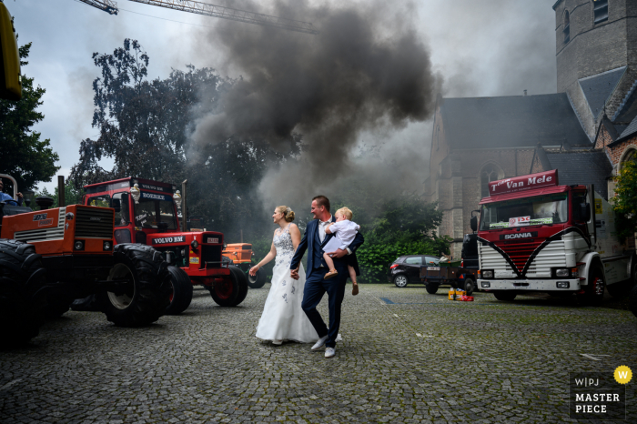 Matrimonio in chiesa di Stekene Immagine della sposa e dello sposo che lasciano l'area con un'enorme quantità di fumo nero che esce da un trattore