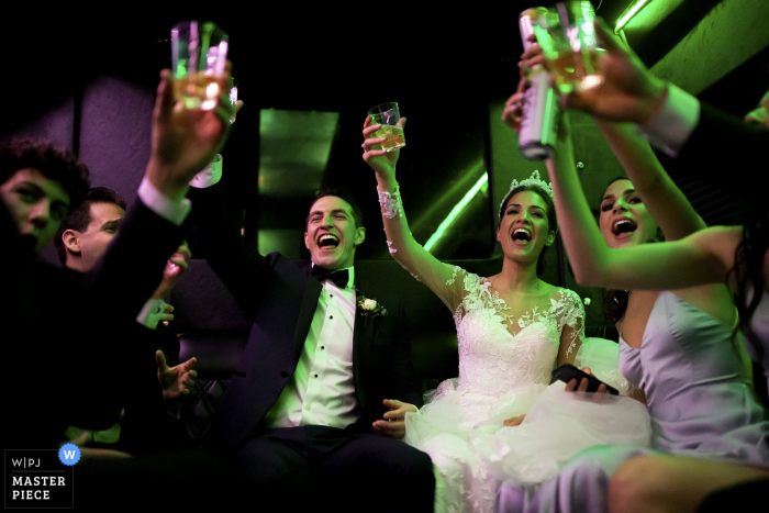 Huwelijksfotografie in Colorado | Het stel proost met hun huwelijksfeest in de limousine op weg naar hun receptie