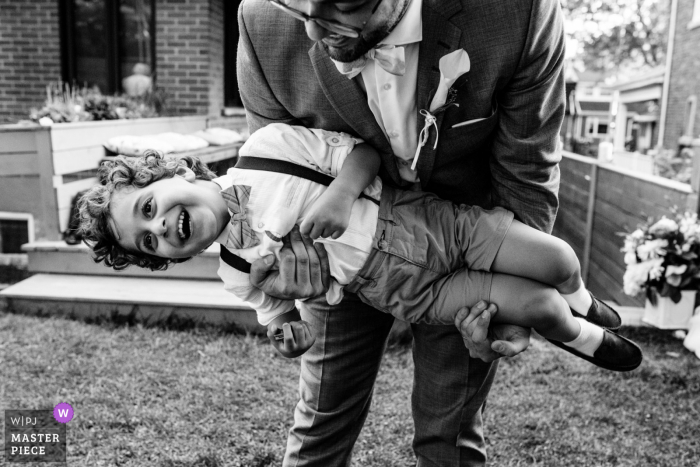 Fotografía de boda al aire libre de Quebec desde un patio trasero en Montreal del novio jugando con su joven sobrino en el patio