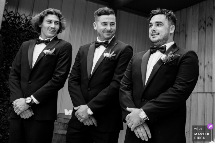 Imagen de la boda de Victoria Australia de dos padrinos de boda observando la reacción del novio cuando la novia entra en la habitación