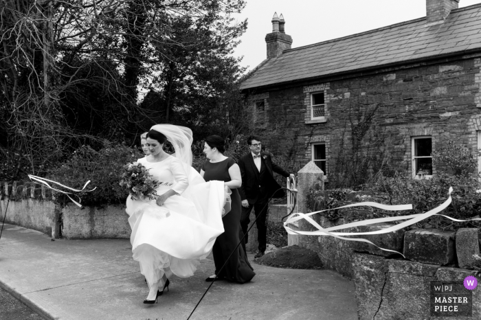 windy day wedding photo from Dublin of the Bride crossing the road to go to the church 