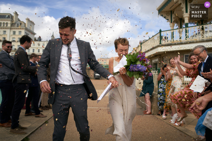 Quiosco de música de Brighton, Fotógrafo de bodas de Brighton | los recién casados ​​corren a través de una lluvia de confeti