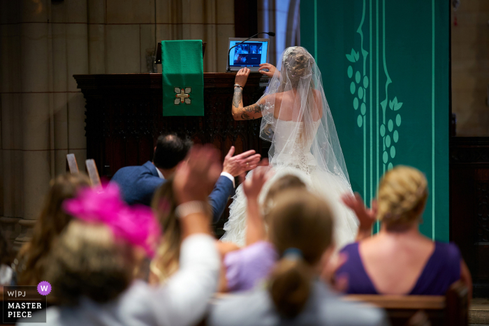 UK wedding photo from a Chiswick, London ceremony during a pandemic - bride getting the laptop link to work mid-ceremony 