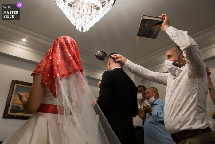 Igdir, Turkey Wedding Photography | Man holding Koran hovering incense over bride and groom's heads Igdir, Turkey Wedding Photography | Man holding Koran hovering incense over bride and groom's heads