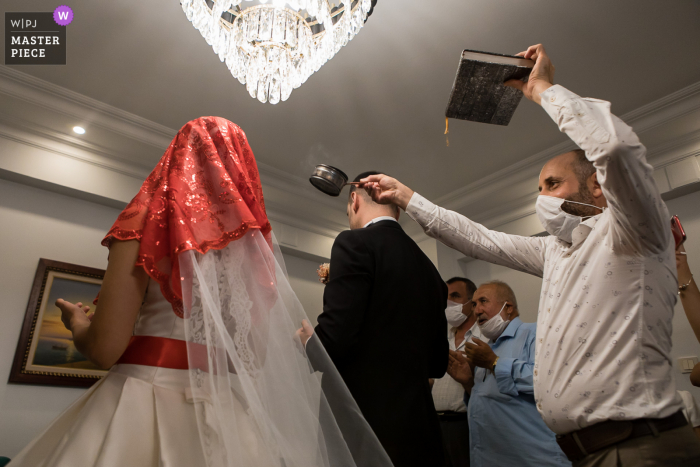 Igdir, Turkey Wedding Photography | Man holding Koran hovering incense over bride and groom's heads 