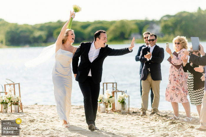 Fotografía de bodas al aire libre de Osterville MA - Dowses Beach of the Bride and Groom caminando por la isla y saludando a sus invitados virtuales