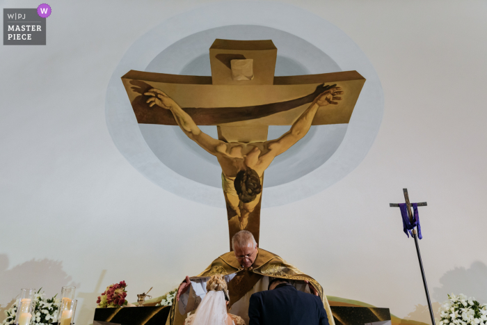 Kerkceremonie trouwfoto uit Brazilië Sao Paulo van een echtpaar dat de zegeningen van de priester ontvangt en het schilderij ziet er ook zo uit