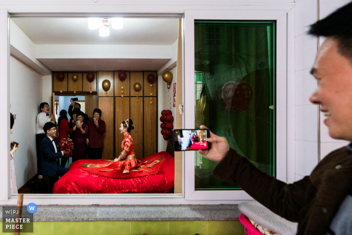 China wedding photography from a Fujian Home of The groom handing the bride a bouquet, but due to Covid-19, he could only tell his oath before the bed. 