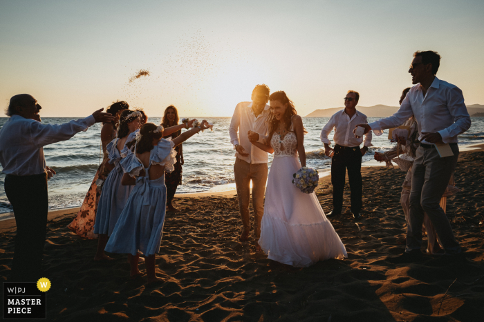 Zdjęcie ślubne z ceremonii zachodu słońca Na plaży w pobliżu Capalbio w Toskanii rzucanie ryżem po bardzo kameralnej uroczystości na plaży