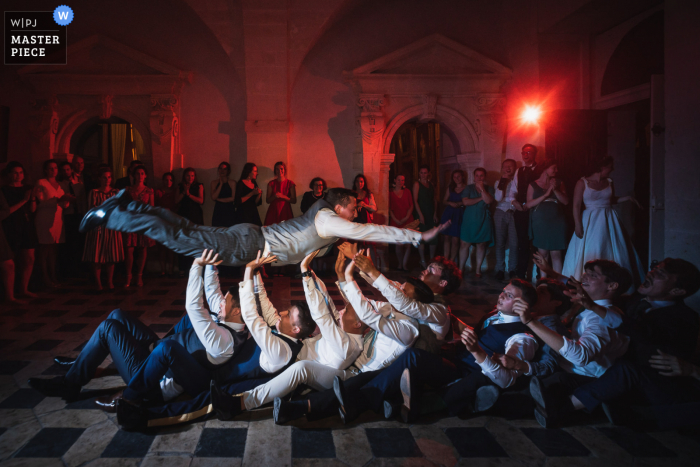 trouwfoto van Château de Brissac, Frankrijk waarop te zien is De bruidegom springt tijdens het feest