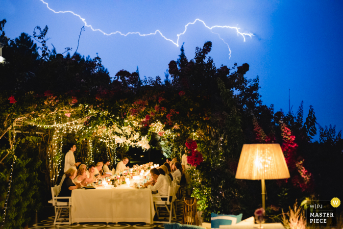 Foto de casamento ao ar livre de um raio na Villa Maçakızı Bodrum / Turquia mostrando convidados do casamento em um jantar em um dia chuvoso