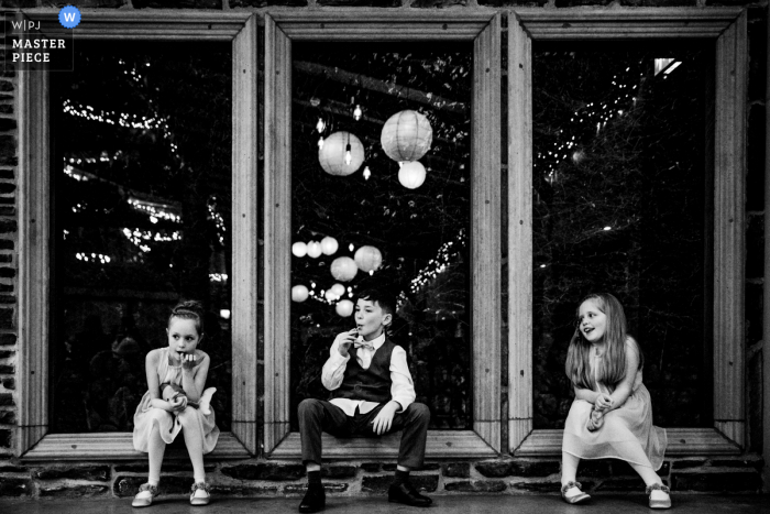 Il fotografo di reportage di matrimonio a Dublino ha creato questa immagine di Segraves Barns di 3 bambini in 3 finestre nella sede del ricevimento