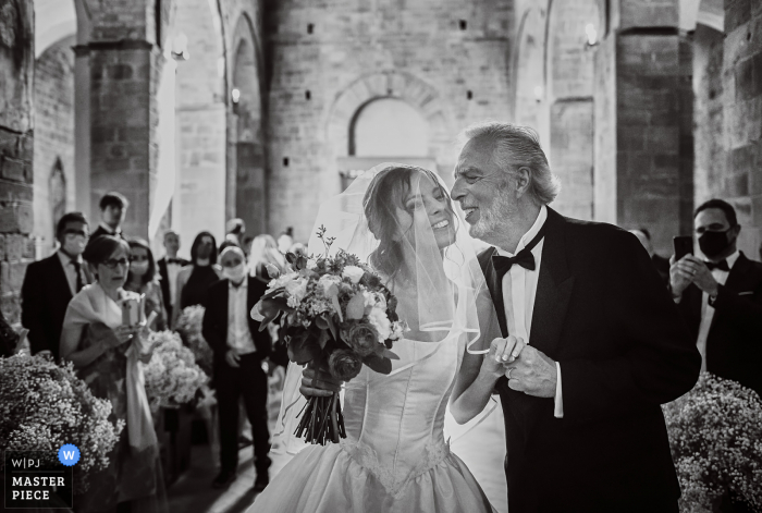 IT fotografía de boda en la Iglesia de Certaldo - Toscana de la novia entra y está a punto de ser besada