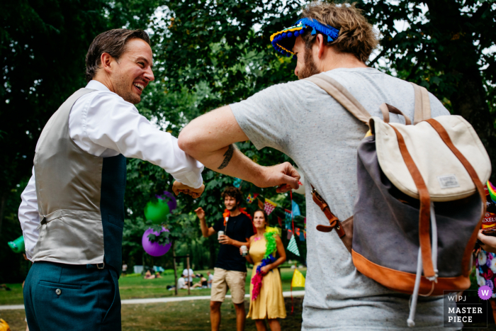 Utrechtse trouwreportagefoto uit Nederland bij de receptie van een bruidegom en gast met een 'coronaproof' felicitatie