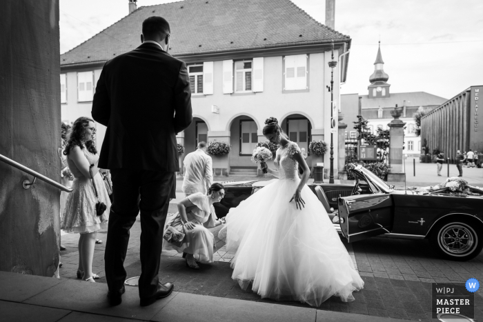 Fotografía de boda desde el ayuntamiento de Brumath, Francia de la novia que llega en un coche descapotable