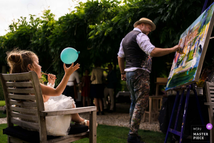 Il fotografo di matrimoni di Utrecht al Kasteel Maurick di Vught scatta immagini della Flowergirl che suona mentre guarda il pittore dal vivo