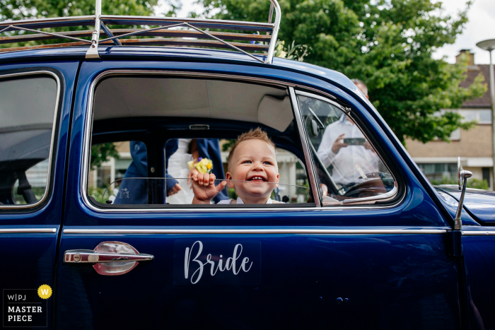 Niederländische Hochzeitsfotografie eines Kindes in einem Hochzeitsauto mit einem Zeichen "Braut"