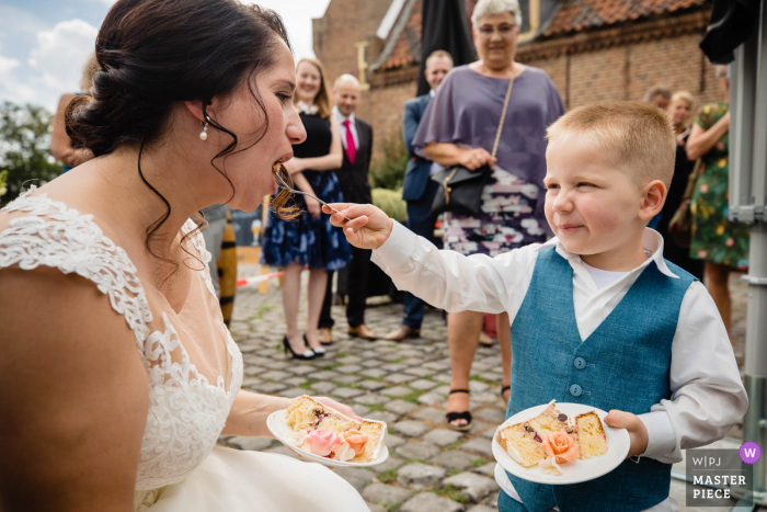 Foto di matrimonio nei Paesi Bassi di un ragazzo che dà da mangiare alla sposa durante il brindisi del ricevimento