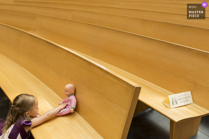 Imagem de uma menina brincando com uma boneca nos bancos da igreja em Oakland Califórnia