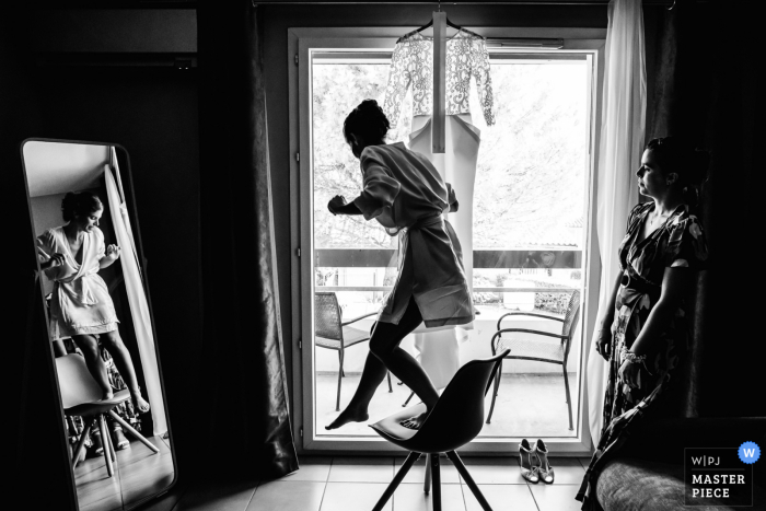 Toulouse, France Bride getting ready image as she steps off a chair by her wedding gown