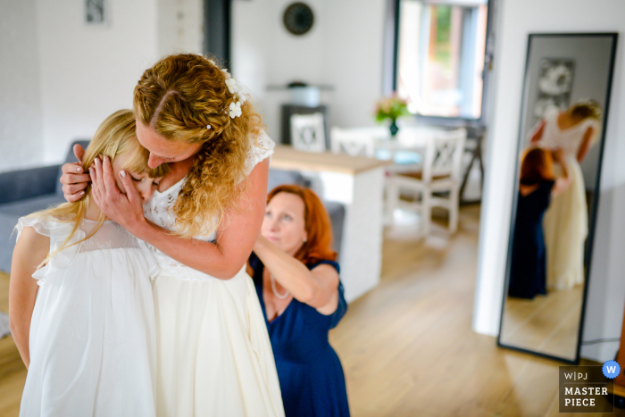 A Hauts-de-France bride reassuring her daughter while her mother closes her wedding dress A Hauts-de-France bride reassuring her daughter while her mother closes her wedding dress