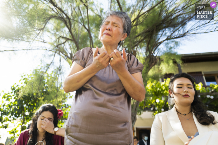 A Auvergne-Rhône-Alpes groom's mother has a strong emotional moment and finalizes a prayer with the groom's sisters on the side