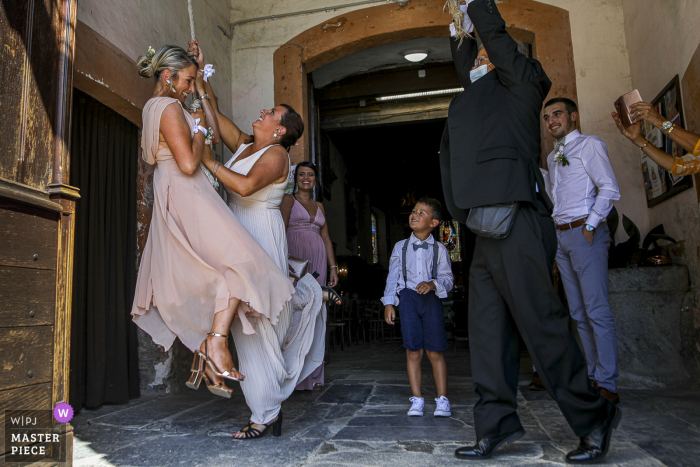 Testigos de la boda de Occitanie están jugando con la campana de la iglesia después de la ceremonia