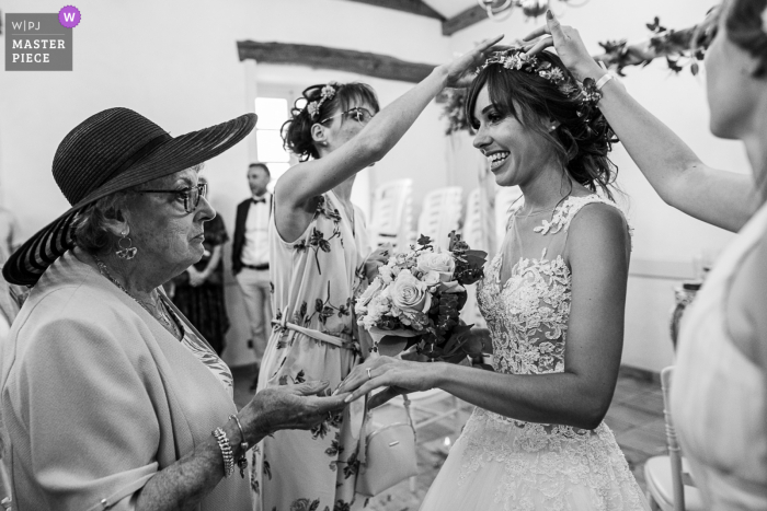 Alors que les demoiselles d'honneur enlèvent les confettis de ses cheveux, la mariée montre son alliance à sa grand-mère au Château de la Rive, Cruet, Savoie, France