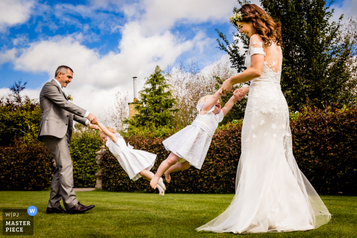 Trouwfoto van de bruid en bruidegom die Mama en Dada zijn en hun twee kleine meisjes ronddraaien tijdens de receptie in Glenview Gardens, Cork, Ierland