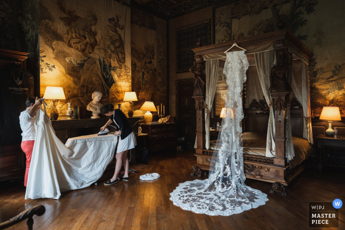 Afbeelding van de bruid die haar jurk strijkt voor haar bruiloft in Château de Brissac, Frankrijk