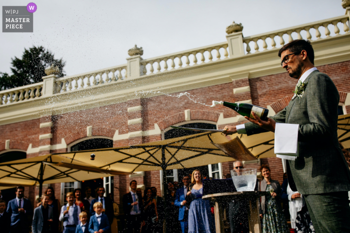 Een bruidegom sabels fles voor toast op de bruiloftsreceptie locatie - oranjerie groot waarschuwsborn