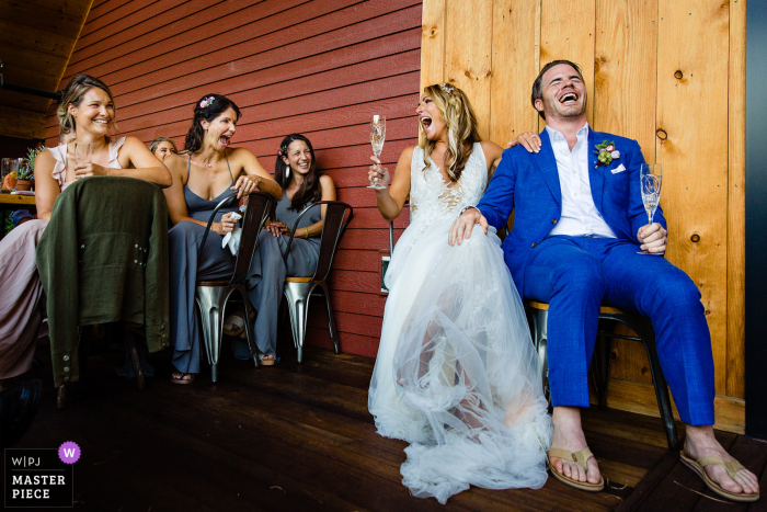 A Scarborough, Maine bride and groom laugh with friends during a wedding reception A Scarborough, Maine bride and groom laugh with friends during a wedding reception