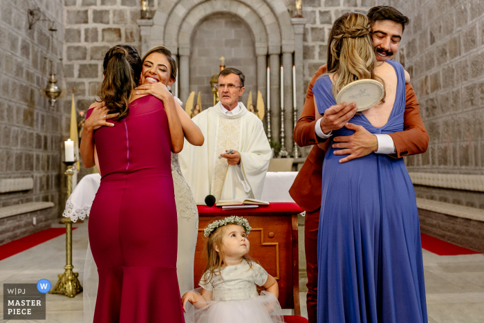 During the Gramado Mother Church wedding ceremony the Bride and groom are hugging bridesmaids and kids get jealous