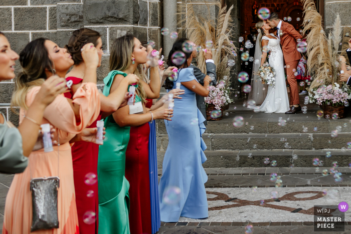 Hochzeitsfoto der Braut und des Bräutigams, die mit Seifenblasen an der Gramado-Mutterkirche küssen