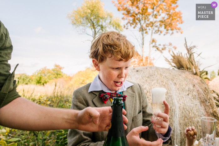 Niño está emocionado y curioso por el burbujeante (sin alcohol) en una boda en Tamworth, Ontario