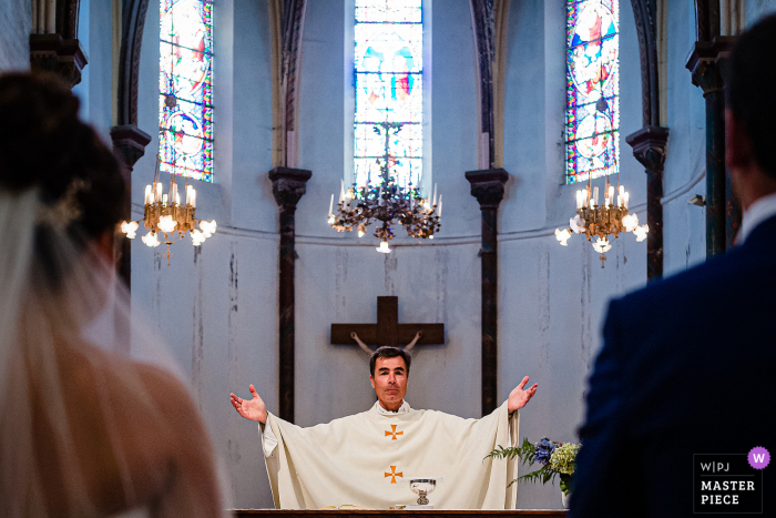 Priest during Mass with arms out of his head for this French wedding ceremony