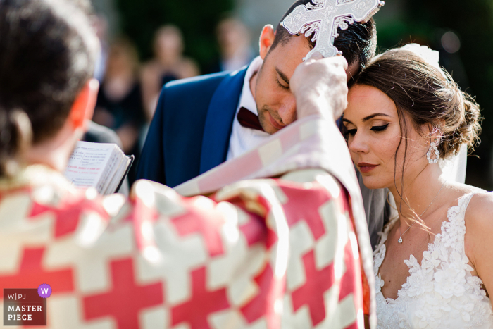 De priester plaatst het kruis op de hoofden van de pasgetrouwden op de ceremonieplaats in Tsarsko