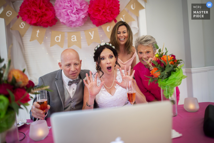 La sposa, lo sposo, la madre della sposa e un amico chattano con gli ospiti durante una linea di ricezione virtuale Zoom presso il Cornelius V. Kelly Community Center