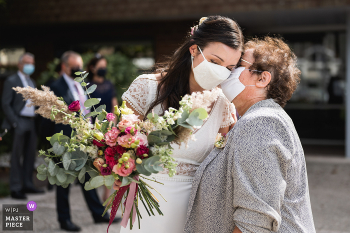 Domaine de Larchey, Frankrijk trouwfoto van een tedere kus met COVID-maskers op