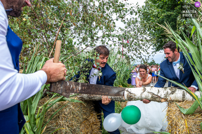 Jogo tradicional francês após a cerimônia nas montanhas da noiva e do noivo serrando um tronco