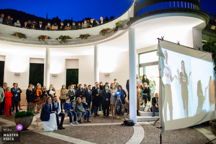 The bride and groom watch a video together with their guests spread over two floors at the Villa Berardi, Vallio Terme