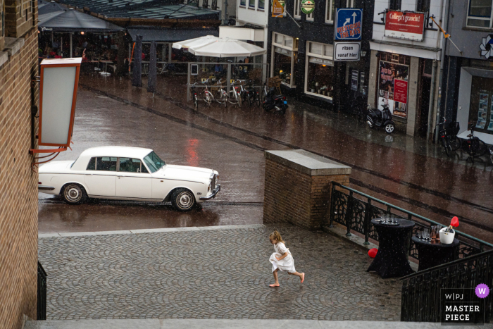 Flowergirl running to shelter from the rain in Hengelo in Overijssel