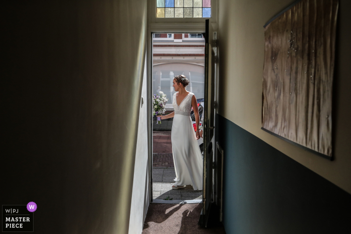 Fotografia di matrimonio di una sposa dell'Aia che esce di casa