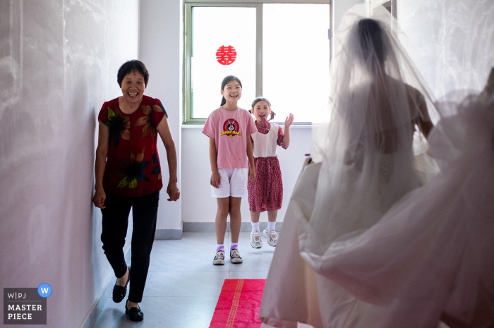 Quando la sposa ha cambiato i suoi vestiti ed era pronta per uscire, i due bambini erano molto felici di vedere la bellissima sposa in Cina