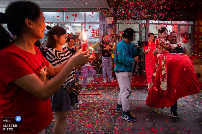 El tío de la novia lleva a la novia al coche, y los familiares y amigos de la novia encienden velas para despedirla en esta imagen del día de la boda china