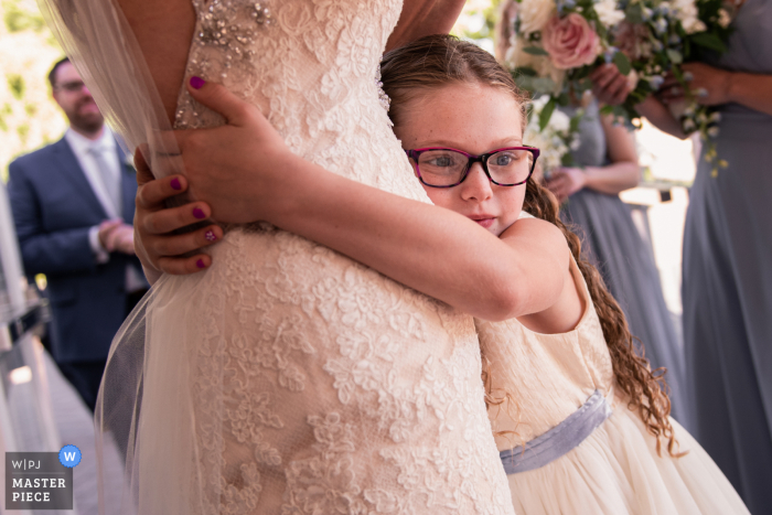 Una giovane ragazza abbraccia la sposa il giorno del suo matrimonio presso The Estate at Eagle Lake NJ